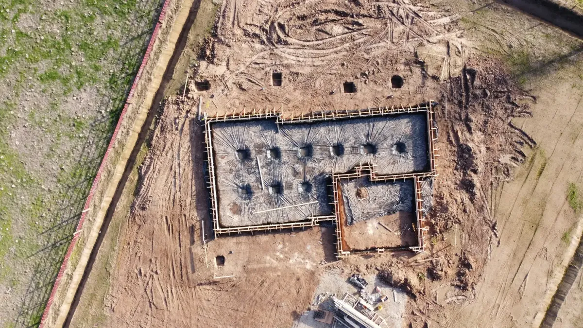 Aerial view of foundation forms and vapor barrier ready for a concrete slab pour on a graded site in farm country